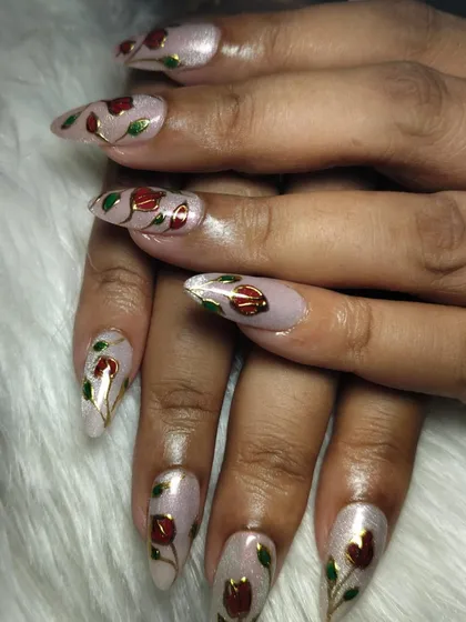 Blossoming beauty, one nail at a time. This elegant design features delicate red roses with gold outlines on long, almond-shaped nail extensions.