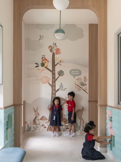 An interactive wall panel and a height chart mural in a nursery corridor. These elements invite children to play and engage with their environment, making the journey between classrooms as fun as the destination.