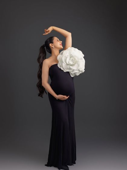 A creative and high-fashion pose. The giant paper flower adds a unique, artistic element to this dramatic solo portrait in black.