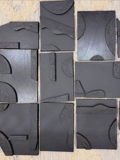 An overview of a multi-panel wall art installation before shipping. Each board has its own unique shape and textured elements, designed to come together as one large, cohesive abstract artwork.