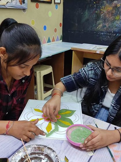 Students working together on a rangoli. Our community is built on mutual support and shared passion for art.