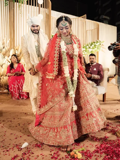 The couple taking their first steps together after the ceremony, showered in petals. This moment, set against the beautiful boho-luxe mandap, is the perfect end to a sacred ceremony.