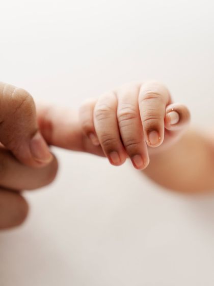 A newborn's hand wrapped tightly around a parent's finger. This instinctive grasp is one of the most precious things to capture.