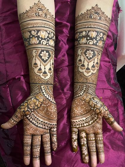 An elegant bridal design featuring beautiful hanging jhumkas and delicate floral bands. The combination of bold figures and fine, detailed fillers gives this mehendi a balanced and sophisticated look.