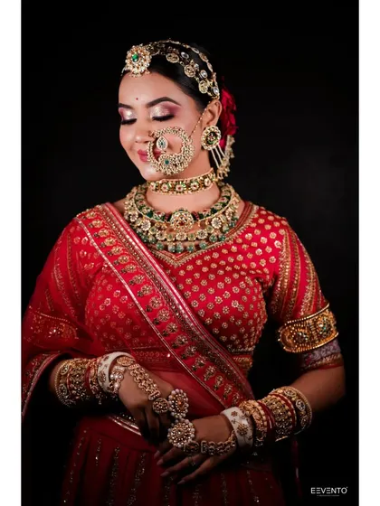 A stunning Rajasthani-inspired bridal look. The heavy jewellery and bright red lehenga are balanced with bold eye makeup and a perfectly defined lip.