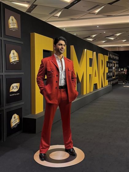 Actor Taaha Shah stands confidently in our custom red suit at the Filmfare awards. The full-length view shows the clean lines and impeccable fit of the trousers and jacket.