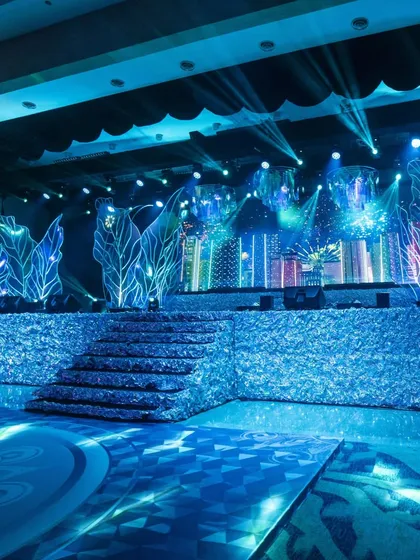 A wider view of the empty Sangeet stage, showing the central steps, the custom floor graphics, and the full expanse of the iridescent and LED backdrop. This highlights the scale and detail of our design before the party begins.