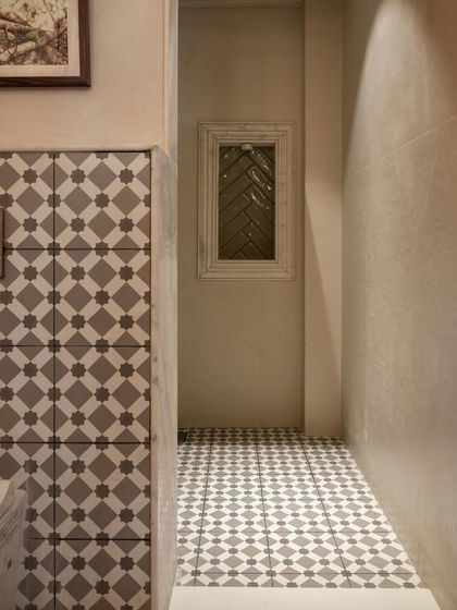 A narrow bathroom space made interesting with patterned floor and wall tiles. A small, framed window with reeded glass allows light to filter through while maintaining privacy.