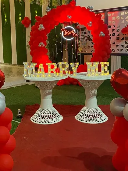 A closer look at a classic proposal setup. The combination of a red balloon arch, a central "Love" neon sign, and glowing "MARRY ME" letters creates a focused and intensely romantic focal point.