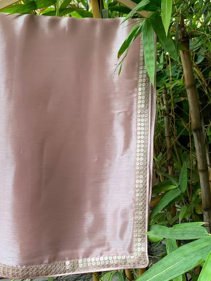 The fabric of our 'Gulabi' saree has a beautiful, subtle sheen, captured here in natural light. The border is hand-embroidered with sequins.