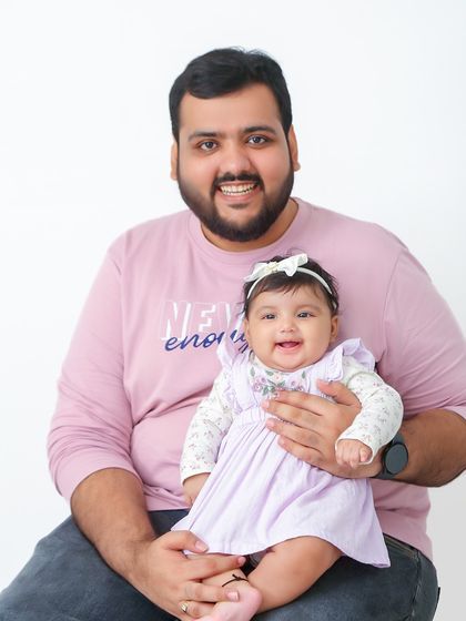 A proud father holds his smiling baby. This image perfectly captures the special bond between a dad and his little one.