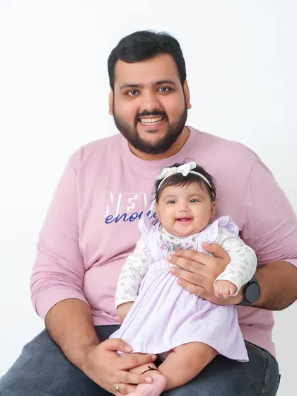 A proud father holds his smiling baby. This image perfectly captures the special bond between a dad and his little one.