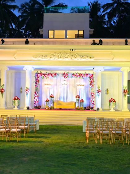 The magnificent reception stage for Cristina and Kevin, set against the backdrop of a beautiful white villa. The open-air lawn setting combined with the grand, floral stage created a truly elegant atmosphere.