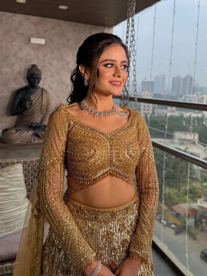 A beautiful portrait by the window, with the city skyline in the background. The golden outfit and glowing makeup look absolutely radiant.