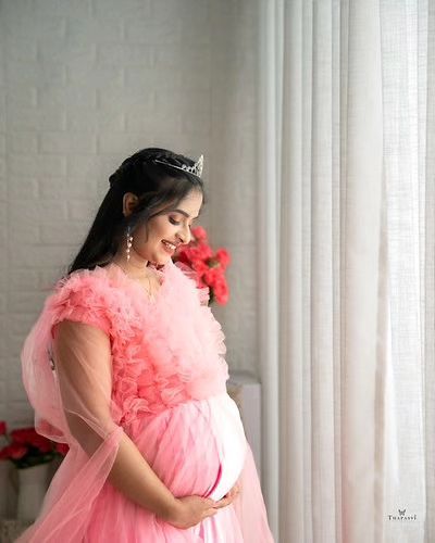 A quiet, reflective moment captured beautifully. The soft lighting complements the delicate details of the pink ruffled gown and the client's princess tiara.