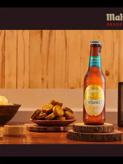 This composition for Mahou Wheat uses wooden elements and a variety of snacks to create a warm, rustic atmosphere, suggesting a relaxed evening with friends.