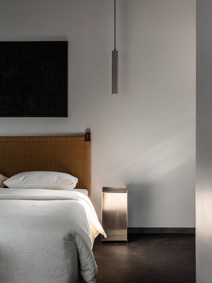 A detail of the master bedroom, showing the handwoven headboard and the sleek, metallic pedestal table I designed. I enjoy pairing rustic, natural textures with clean, industrial materials.