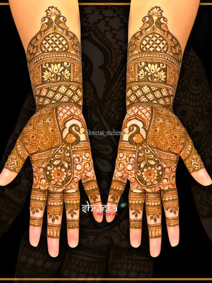 A beautiful example of a traditional peacock mehendi design. The symmetrical pattern on both hands is filled with fine details and classic paisley motifs.