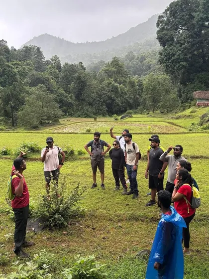 The trek leader briefing the group in a beautiful valley, surrounded by green fields and mountains.