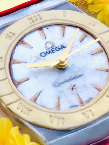 A close-up of the Omega watch cake face, showing the incredible detail of the logo, hands, and hour markers.