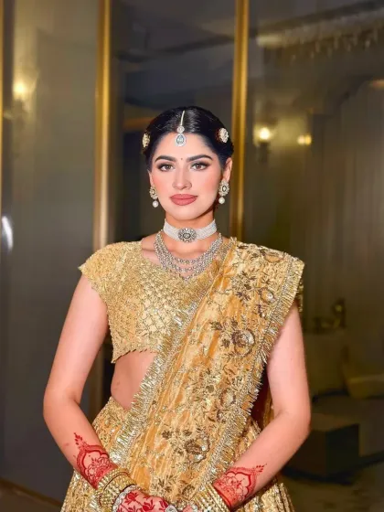 A full-length portrait of the bride in her golden lehenga. The styling is classic and timeless, with a focus on the intricate craftsmanship of the outfit.
