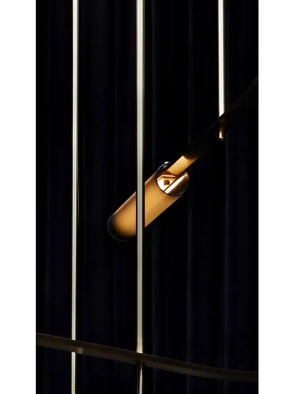 A close-up detail of a single Volant light, showing the textured glass tube and the delicate brass clip that holds it in place.