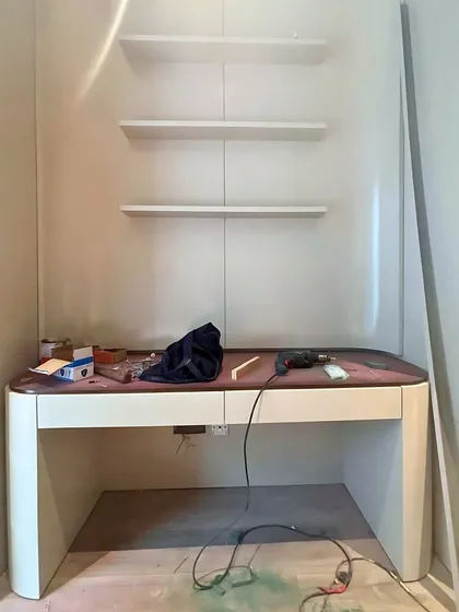 A custom desk and shelving unit being installed. This image shows the transition from raw construction to the installation of bespoke furniture pieces that will define the character of the room.