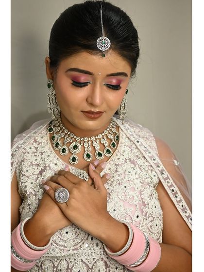 A close-up of this stunning white lehenga with intricate threadwork. It's paired with a contrasting green and diamond-look jewellery set, which I provide with the rental.