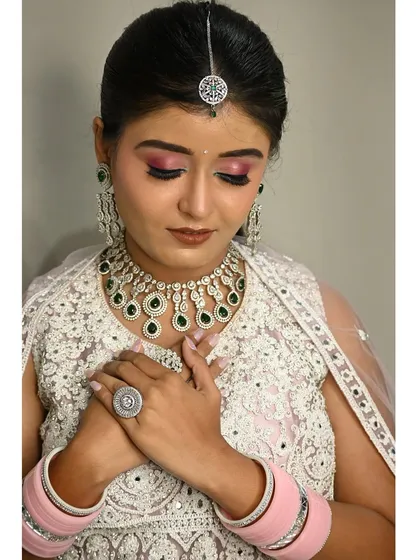 A close-up of this stunning white lehenga with intricate threadwork. It's paired with a contrasting green and diamond-look jewellery set, which I provide with the rental.