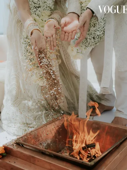 A close-up of a traditional ritual during the Mauritius wedding, featured in Vogue India. This shot focuses on the hands of the couple as they participate in the sacred fire ceremony, highlighting cultural details.