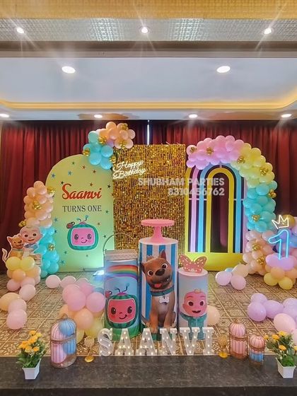 A grand Cocomelon stage setup in a party hall, featuring a gold sequin wall, multiple backdrops, and character-themed props.