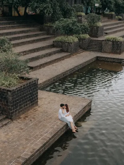 An intimate moment by the water's edge at a serene ghat-style location. This high-angle shot creates a sense of peace and seclusion within the bustling city.