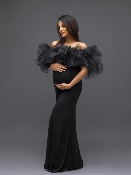 A stunning solo portrait in a dramatic black ruffled gown, exuding elegance and high fashion.