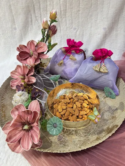 A simple yet elegant Diwali hamper. This beautiful tray holds a decorative bowl of premium almonds and two floral 'potlis', perfect for a sophisticated and thoughtful gift.