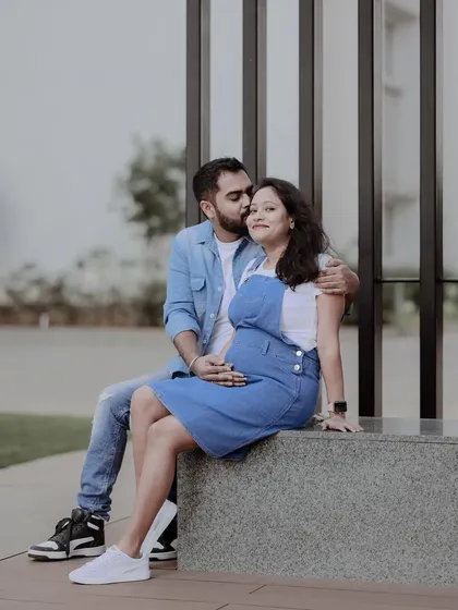 A sweet, candid moment from the same casual maternity shoot. The kiss on the cheek adds a layer of affection and intimacy.