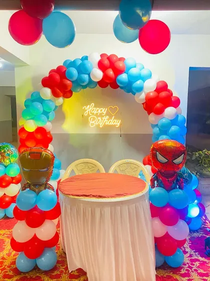 A superhero-themed birthday decoration featuring a balloon arch with Spiderman and Ironman character balloons.