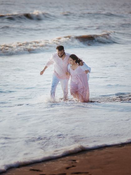 A candid shot of a couple laughing as they wade through the ocean waves during their beach pre-wedding shoot.