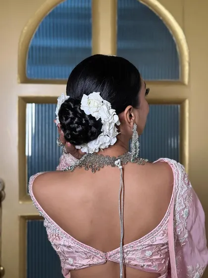 A detailed shot of a classic bridal bun, intricately braided and adorned with a circle of fresh white flowers. This style is a beautiful choice for a traditional wedding ceremony.