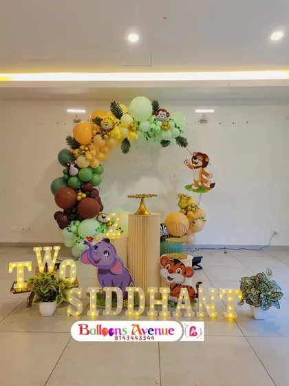 The full setup for Siddhant's second birthday, featuring a jungle-themed balloon ring, cartoon animal cutouts, and a light-up name display.