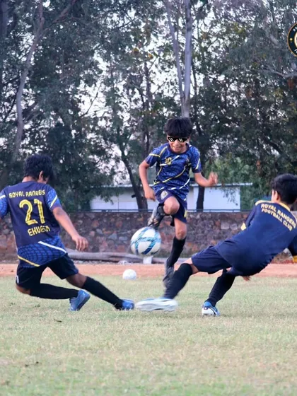 A dynamic moment in a training scrimmage as one player skillfully evades two sliding tackles. Our practice games are designed to be competitive and fun, simulating real match pressure.