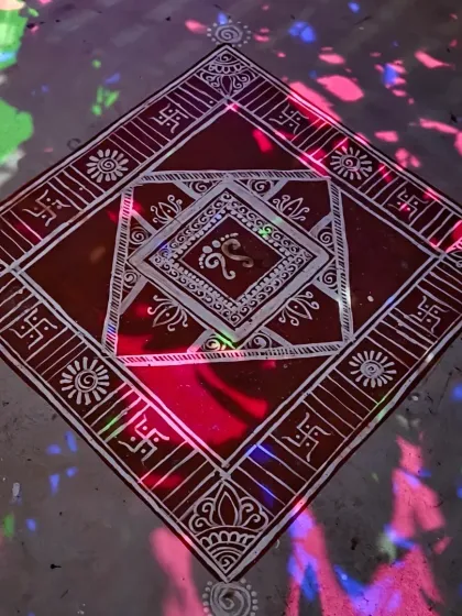 The finished Mandana seen under colorful disco lights, adding a modern, festive twist to the traditional artwork. The white lines of the design stand out sharply against the earthy red base.