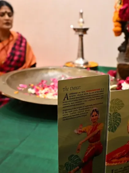 The Gejjai Puja setup, with the performance brochure in the foreground. This ritual is an intimate gathering for family to witness the student's readiness and to offer their blessings.