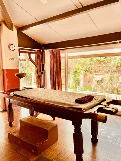 This is one of our authentic therapy rooms, featuring a traditional wooden Droni table used for treatments like Abhyanga and Shirodhara. The space is designed to be both functional and deeply calming.