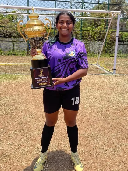 A player proudly holds the massive Global Cup 2025 trophy after our U17 team's victory in Goa.