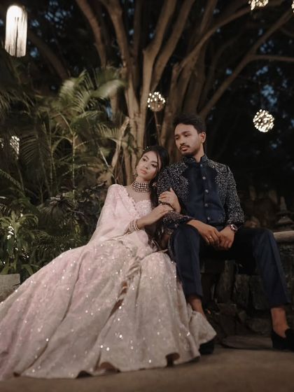 A romantic night-time portrait of the couple at their Sangeet, seated under elegant lighting.