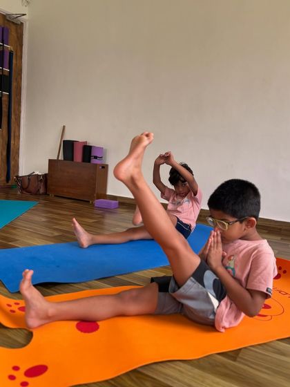 This young student is practicing a seated leg lift, which helps build core strength and hamstring flexibility. We always focus on moving our bodies in new and beneficial ways.