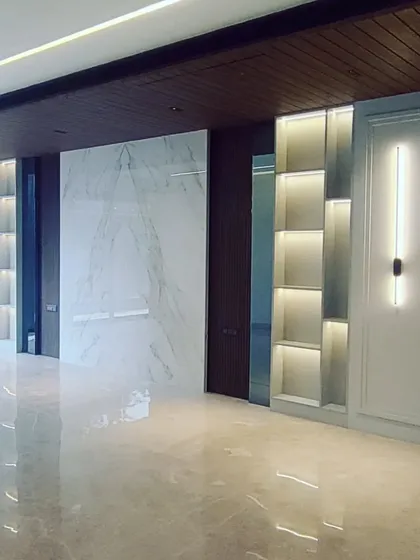 This image captures the moment when lighting and built-in features are installed. The backlit shelving and marble wall panel are in place, demonstrating how different materials come together.