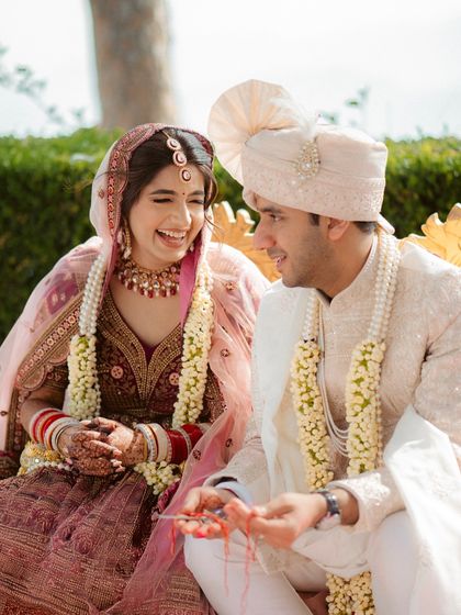 A candid shot of the bride and groom laughing together during a wedding ritual, capturing their genuine connection.