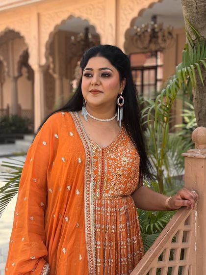 A stunning party look for a client in a vibrant orange anarkali. The makeup is warm and glowing, with a bronze eyeshadow and a nude lip.