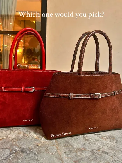 I love offering choices that reflect different moods. Here are two of our suede Demi bags, one in a vibrant Cherry Suede and the other in a rich Brown Suede, each featuring a delicate buckle and a utilitarian round leather handle.